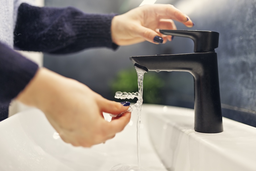person rinsing clear aligners to clean invisalign clear aligners and care for clear aligners